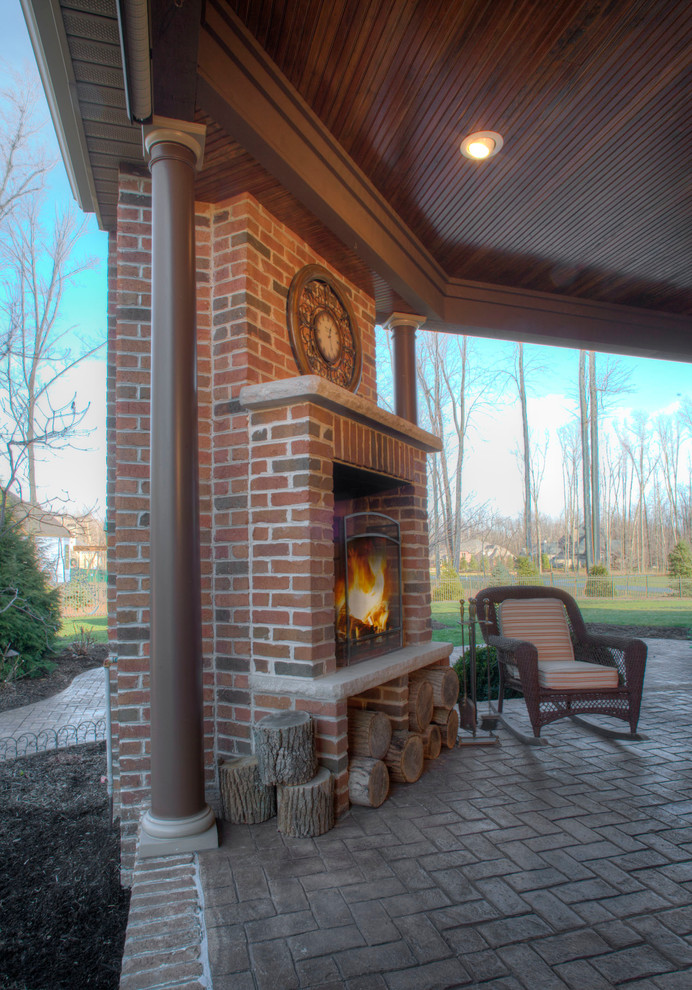 Photo of a large traditional back patio in Cleveland with a fire feature, brick paving and a roof extension.