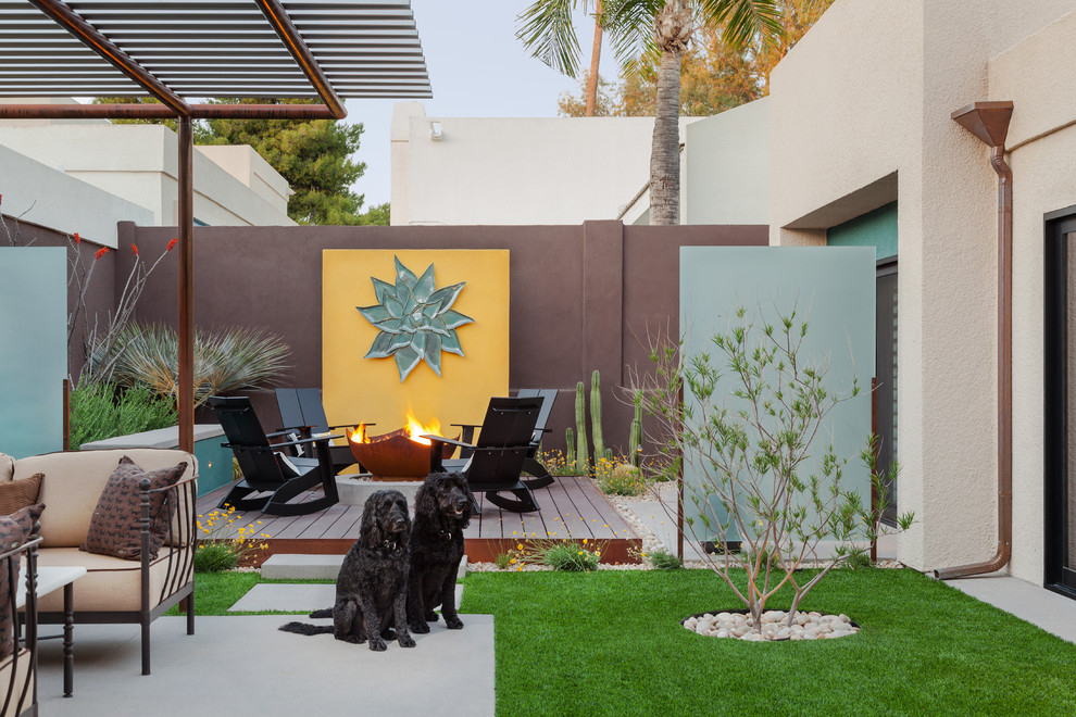 Exemple d'une grande terrasse arrière tendance avec un foyer extérieur et une extension de toiture.