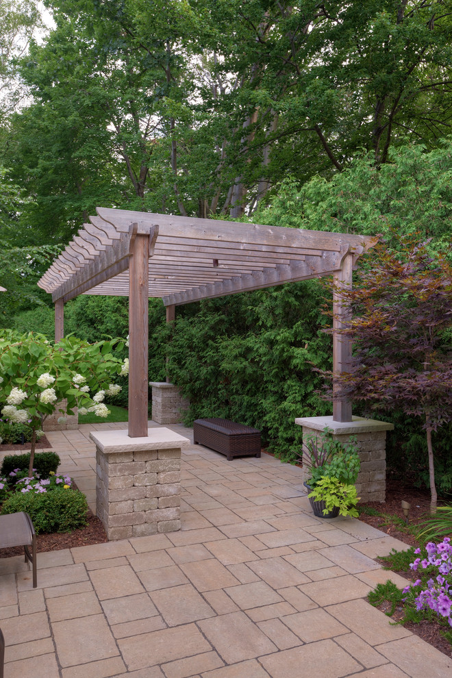 This is an example of a traditional patio in Toronto with natural stone paving and a pergola.