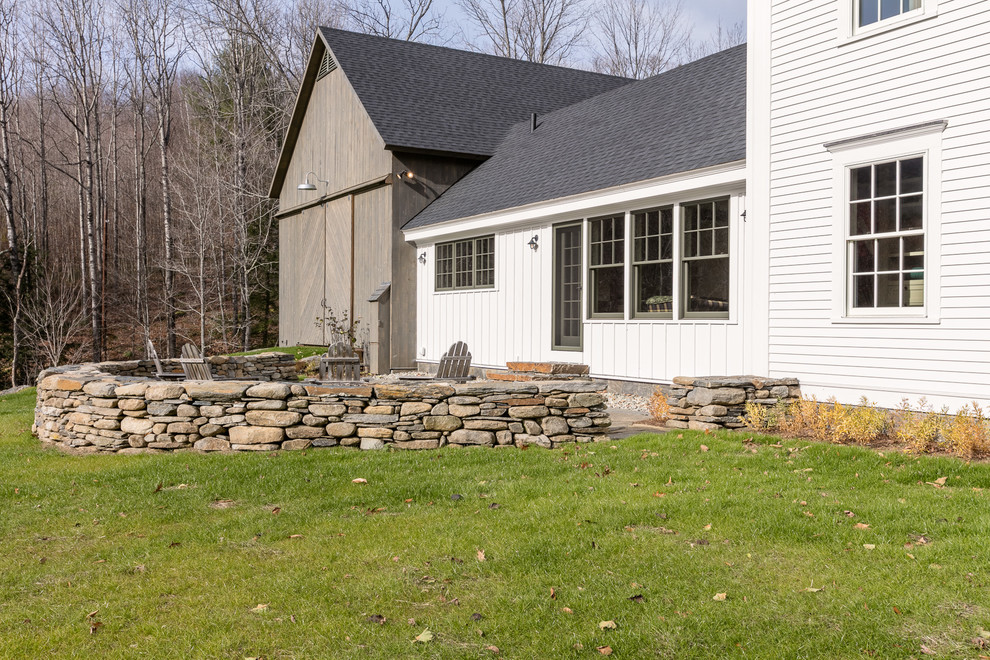 Ejemplo de patio de estilo de casa de campo de tamaño medio sin cubierta en patio trasero con adoquines de piedra natural
