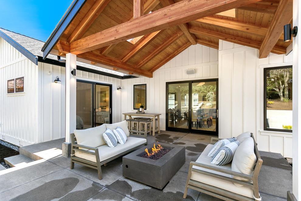 Cette photo montre une terrasse arrière nature de taille moyenne avec un foyer extérieur, une dalle de béton et une extension de toiture.