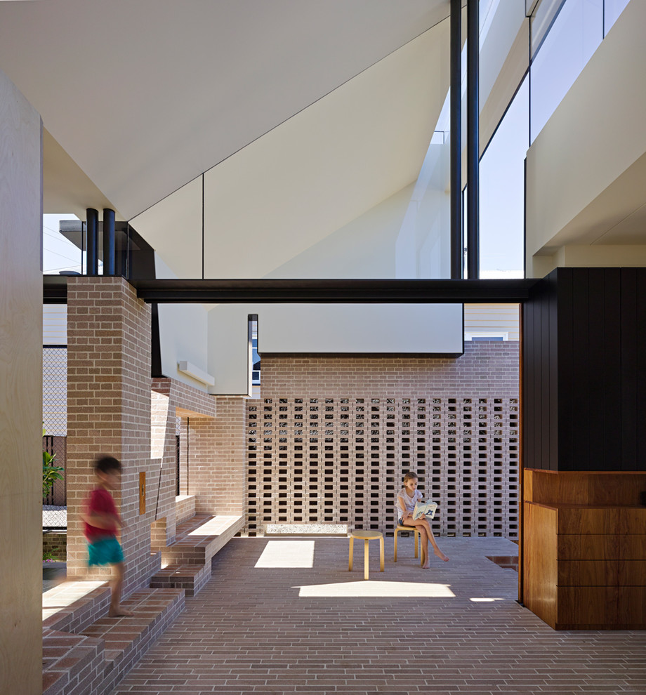 Cette image montre une terrasse design avec des pavés en brique et une extension de toiture.