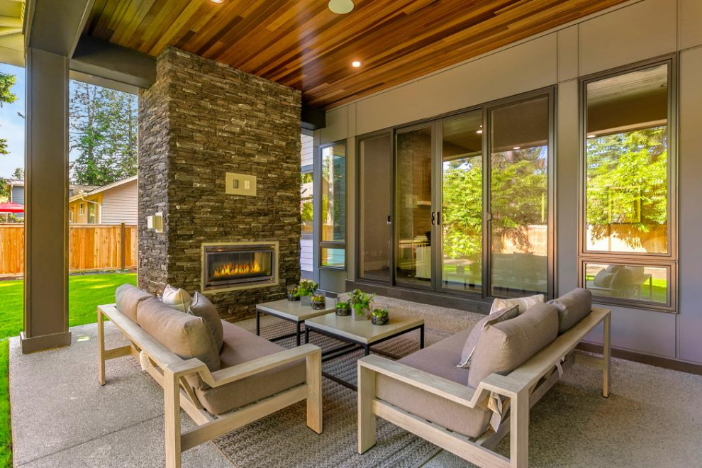 Inspiration for a large modern back patio in Seattle with a fireplace, concrete slabs and a roof extension.