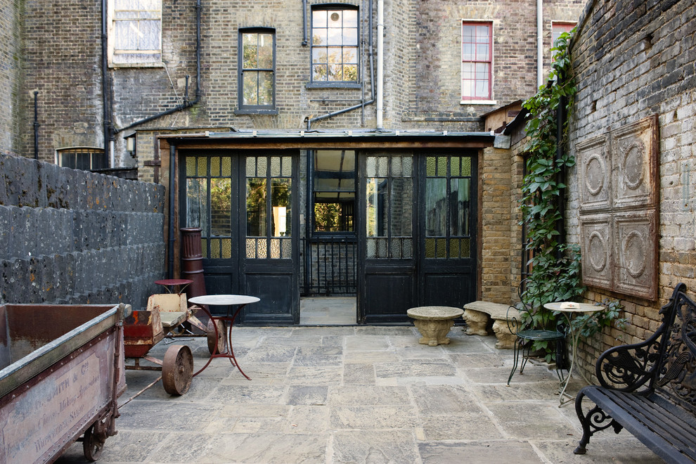Rustic courtyard patio in London with no cover.