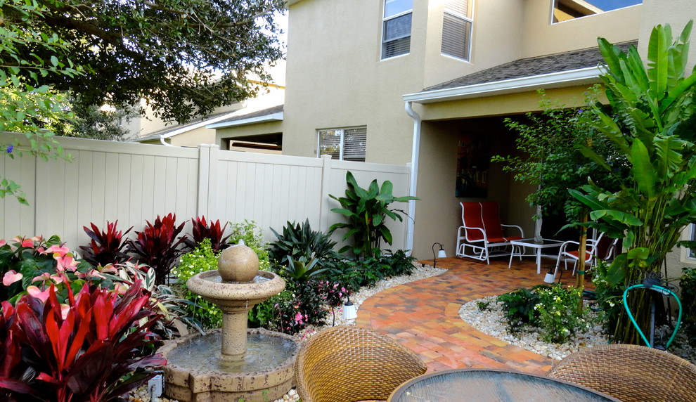 Idee per un patio o portico tropicale dietro casa e di medie dimensioni con pavimentazioni in mattoni, fontane e un tetto a sbalzo