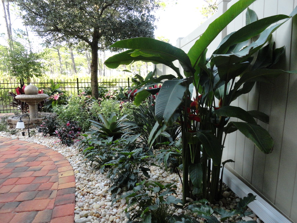 Modelo de patio tropical de tamaño medio en patio trasero y anexo de casas con fuente y adoquines de ladrillo
