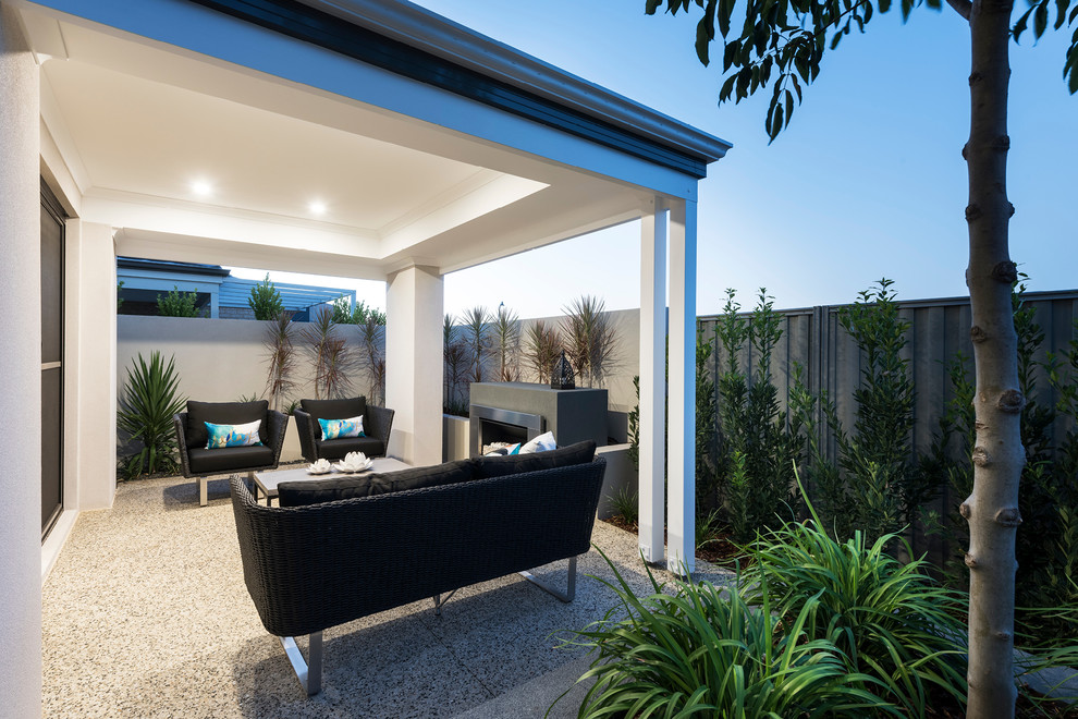 Inspiration pour une terrasse arrière minimaliste de taille moyenne avec un foyer extérieur, une dalle de béton et une extension de toiture.