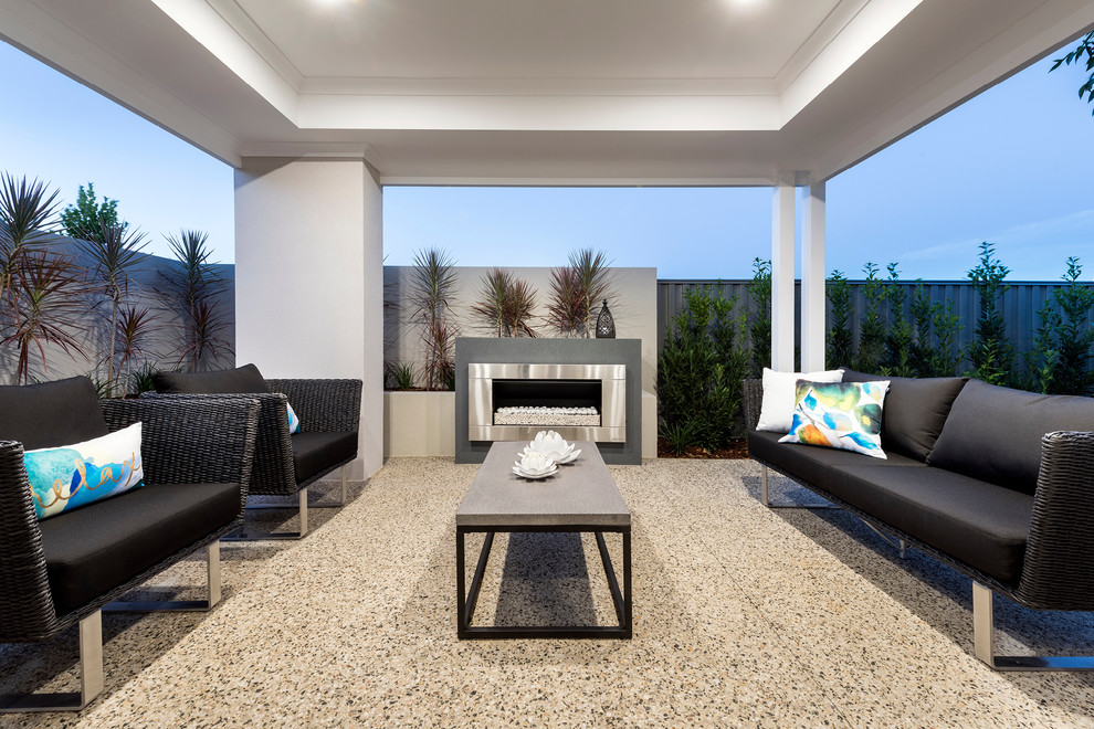 Idée de décoration pour une terrasse arrière minimaliste de taille moyenne avec un foyer extérieur, une dalle de béton et une extension de toiture.