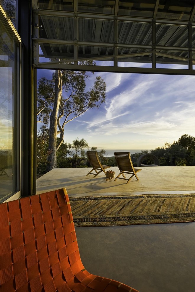 На фото: двор в современном стиле с покрытием из бетонных плит и навесом с