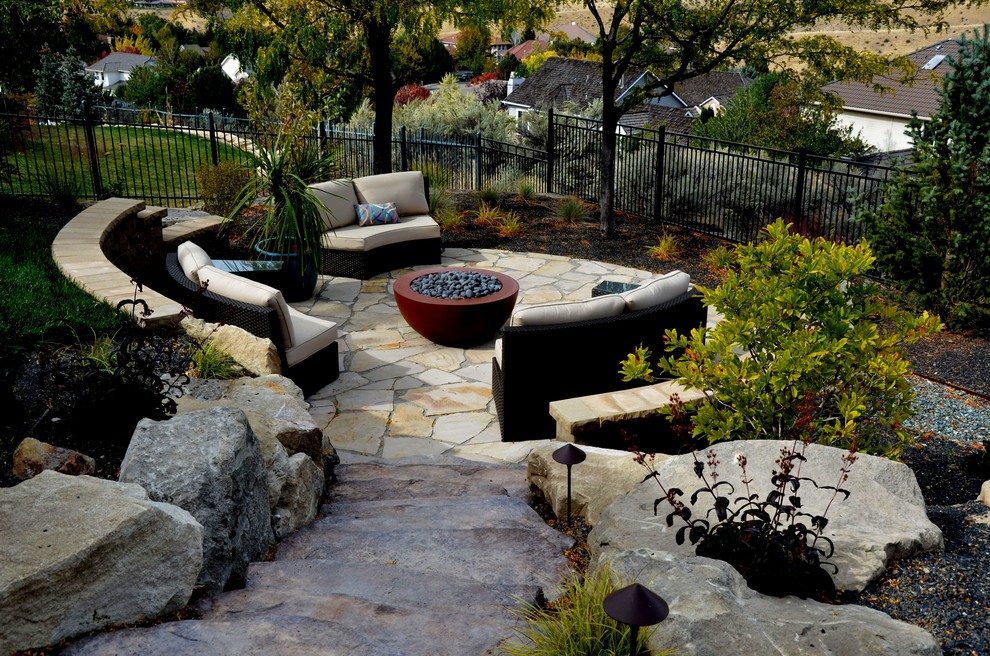 Ejemplo de patio actual de tamaño medio sin cubierta en patio trasero con brasero y adoquines de piedra natural