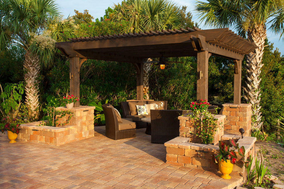 Immagine di un ampio patio o portico classico dietro casa con un focolare, pavimentazioni in pietra naturale e una pergola