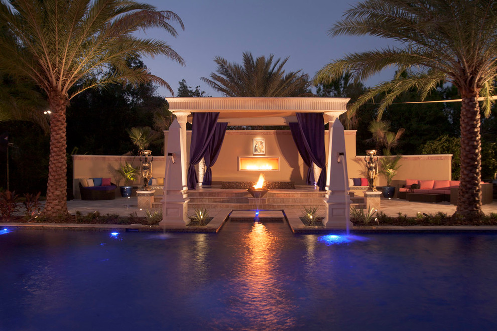 Photo of a large mediterranean back patio in Tampa with a fire feature, natural stone paving and a pergola.