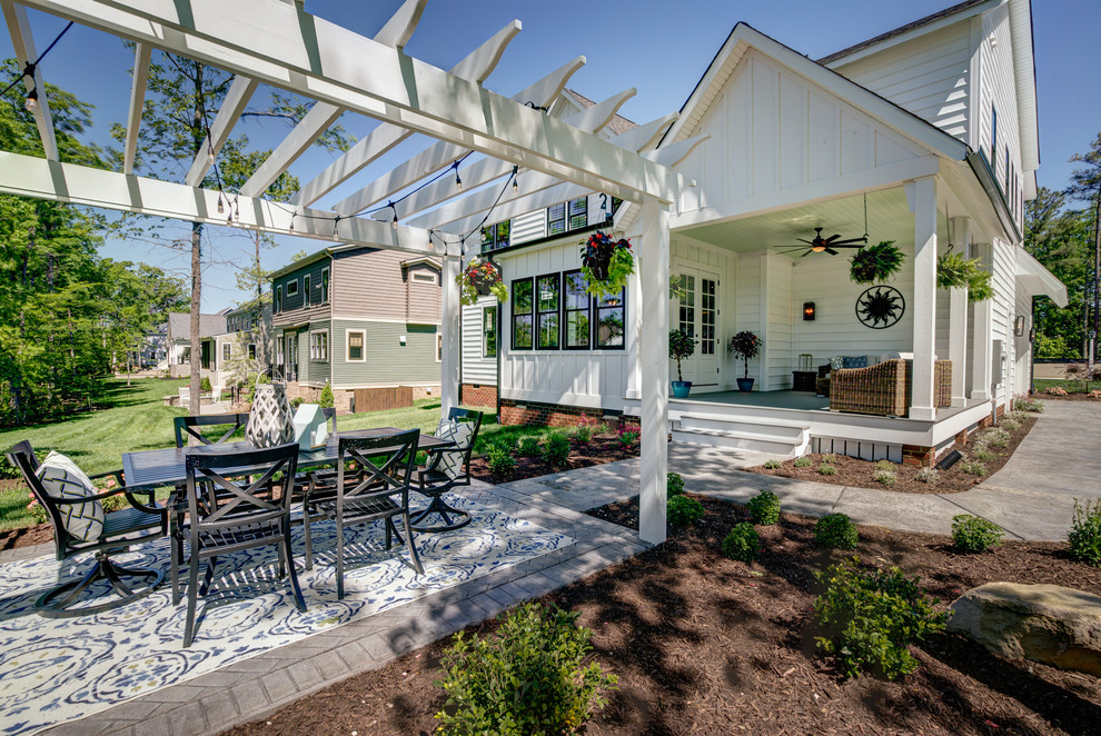 Immagine di un patio o portico country di medie dimensioni e dietro casa con cemento stampato e una pergola
