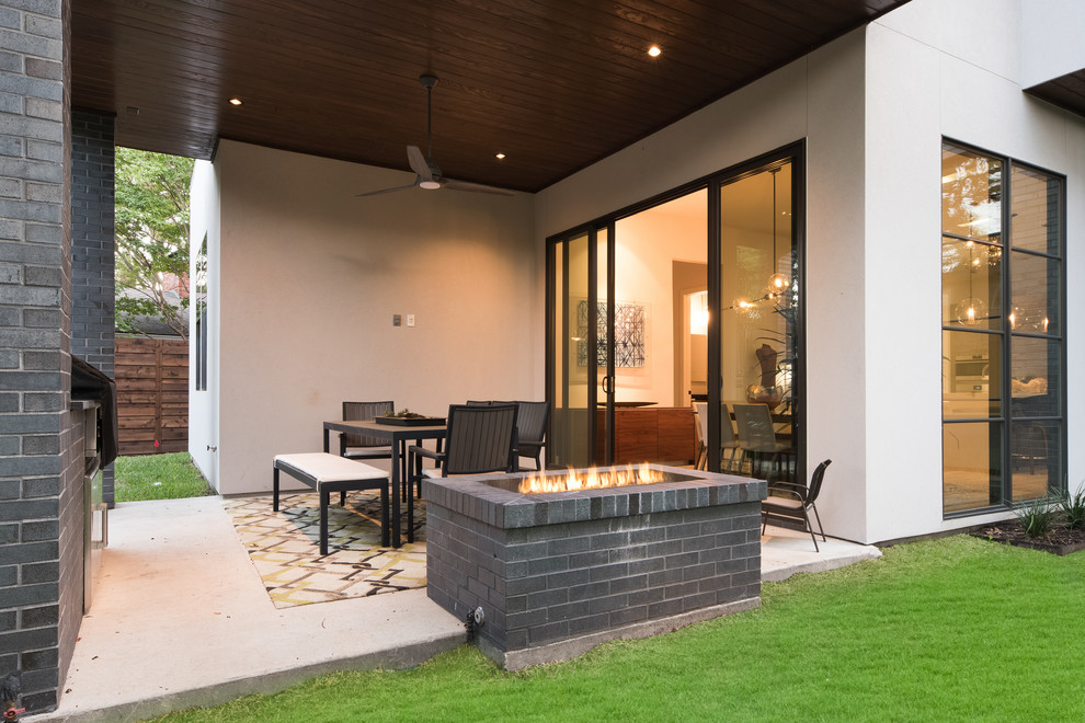 Ispirazione per un patio o portico contemporaneo di medie dimensioni e dietro casa con un focolare, pavimentazioni in cemento e un tetto a sbalzo