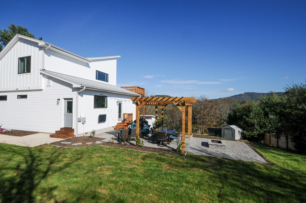 Inspiration pour une terrasse arrière rustique de taille moyenne avec un foyer extérieur, des pavés en béton et une pergola.