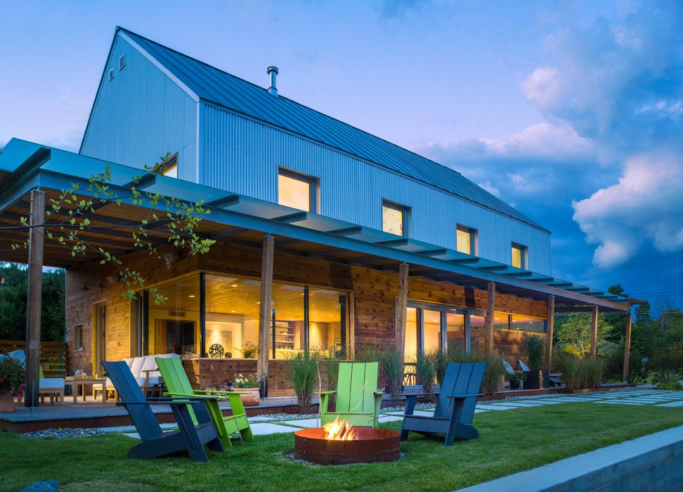 Réalisation d'une terrasse arrière minimaliste avec un foyer extérieur et une extension de toiture.