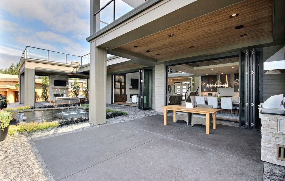 Идея дизайна: огромный двор на заднем дворе в современном стиле с летней кухней, покрытием из декоративного бетона и навесом