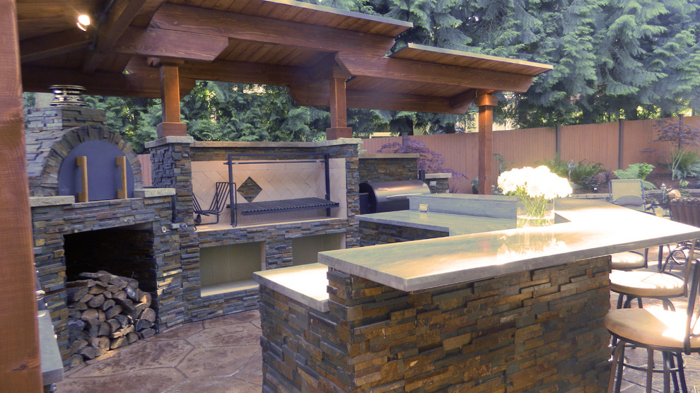 Photo of a medium sized contemporary back patio in Seattle with an outdoor kitchen, stamped concrete and a roof extension.