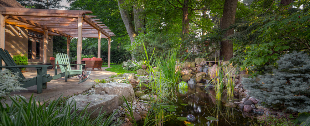 Example of a large classic backyard stone patio design in Toronto with a fire pit and a pergola