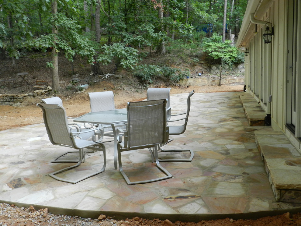 This is an example of a small mediterranean back patio in Raleigh with a vegetable patch, natural stone paving and no cover.