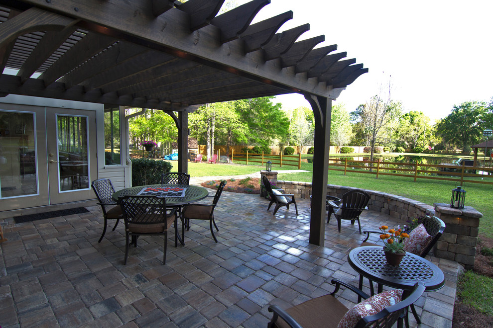 Diseño de patio tradicional grande sin cubierta en patio trasero con jardín de macetas y adoquines de piedra natural