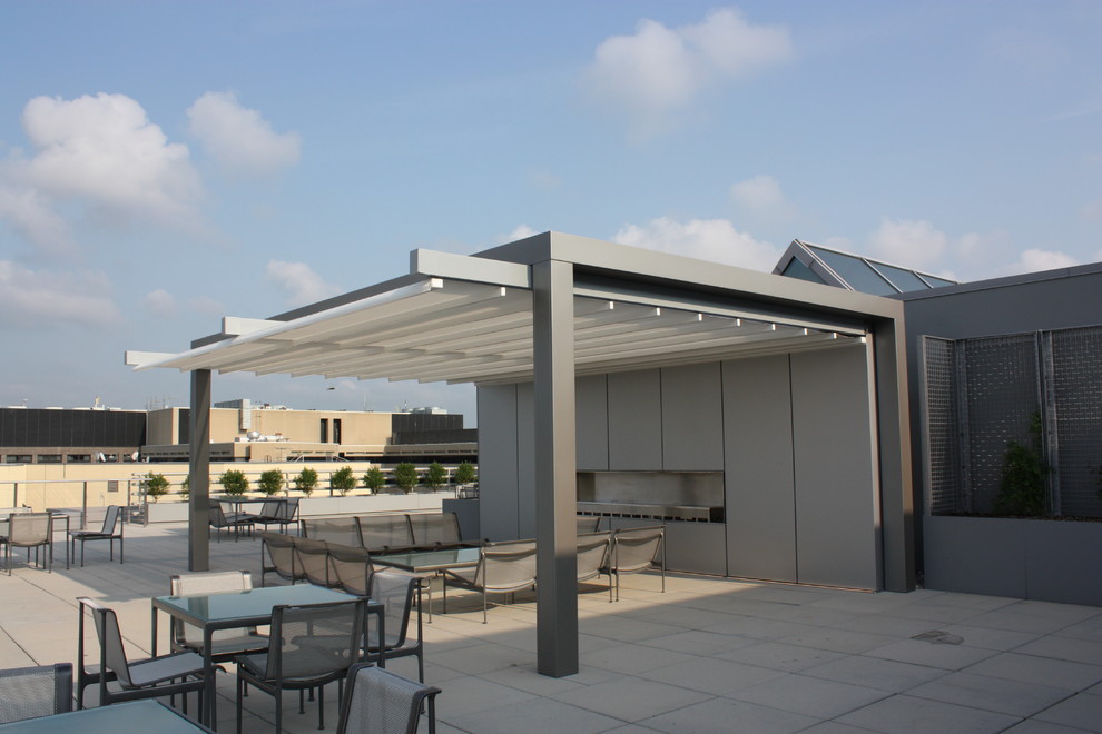 Large modern back patio in DC Metro with a fire feature, concrete paving and an awning.