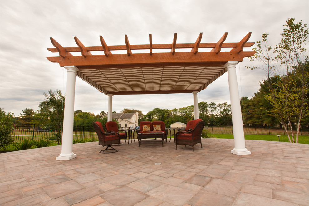 Inspiration for a large traditional back patio in Philadelphia with natural stone paving and a pergola.