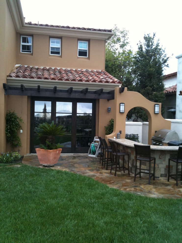 Immagine di un patio o portico mediterraneo di medie dimensioni e dietro casa con pavimentazioni in pietra naturale e una pergola