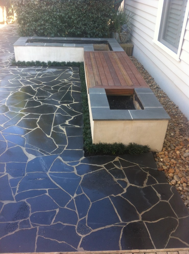 Imagen de patio contemporáneo de tamaño medio sin cubierta en patio trasero con adoquines de piedra natural