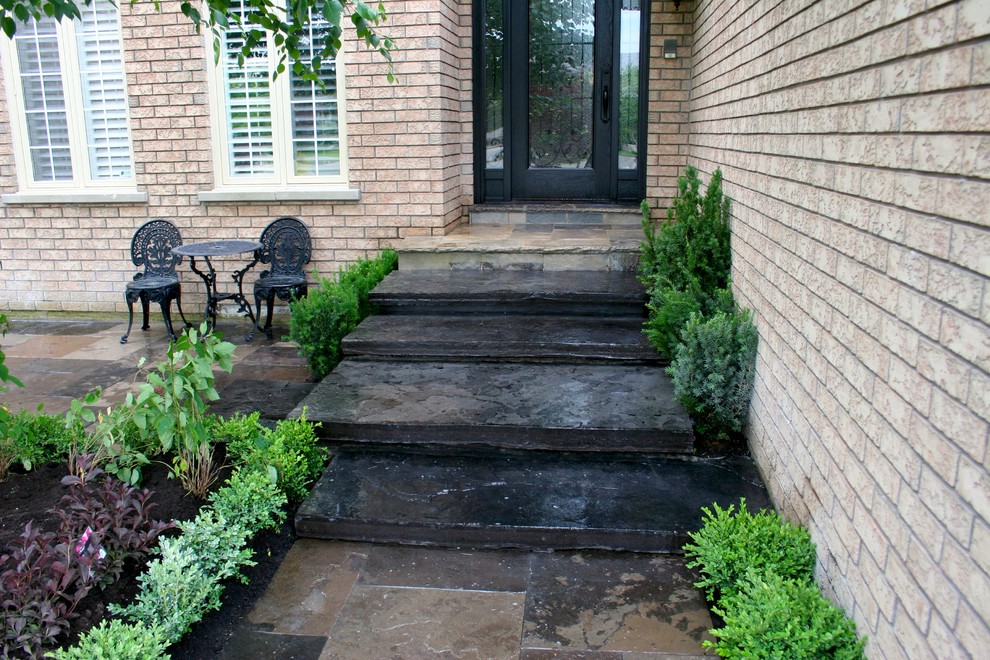 Photo of a medium sized contemporary side patio in Toronto with natural stone paving and no cover.