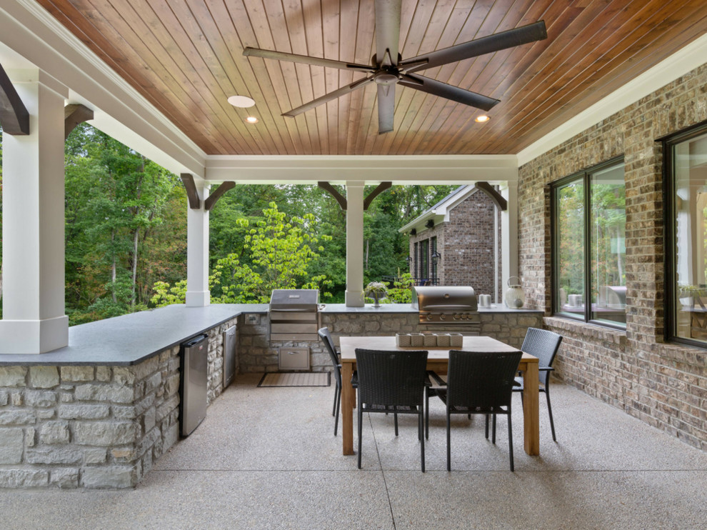 Immagine di un patio o portico tradizionale di medie dimensioni e dietro casa con un caminetto, cemento stampato e un tetto a sbalzo