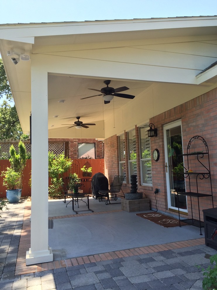Esempio di un patio o portico tradizionale di medie dimensioni e dietro casa con pavimentazioni in cemento e un tetto a sbalzo