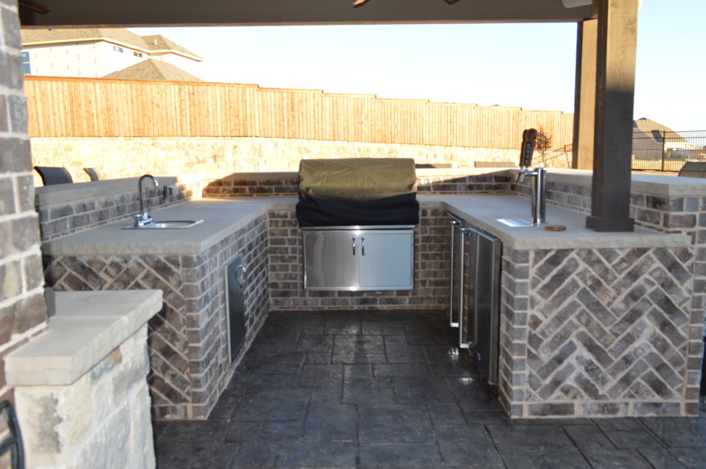 Exemple d'une grande terrasse arrière éclectique avec une cuisine d'été, du béton estampé et une extension de toiture.
