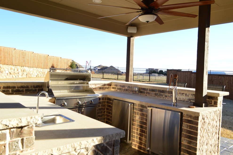Cette photo montre une grande terrasse arrière éclectique avec une cuisine d'été, du béton estampé et une extension de toiture.