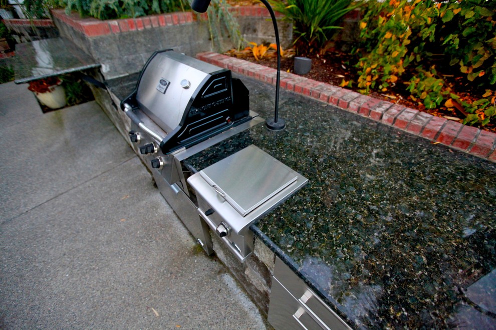 This is an example of a traditional patio in Seattle with an outdoor kitchen, concrete slabs and no cover.