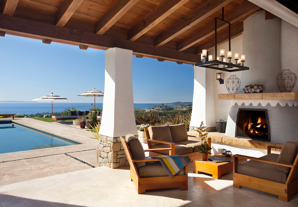 Cette image montre une terrasse méditerranéenne avec un foyer extérieur et une extension de toiture.