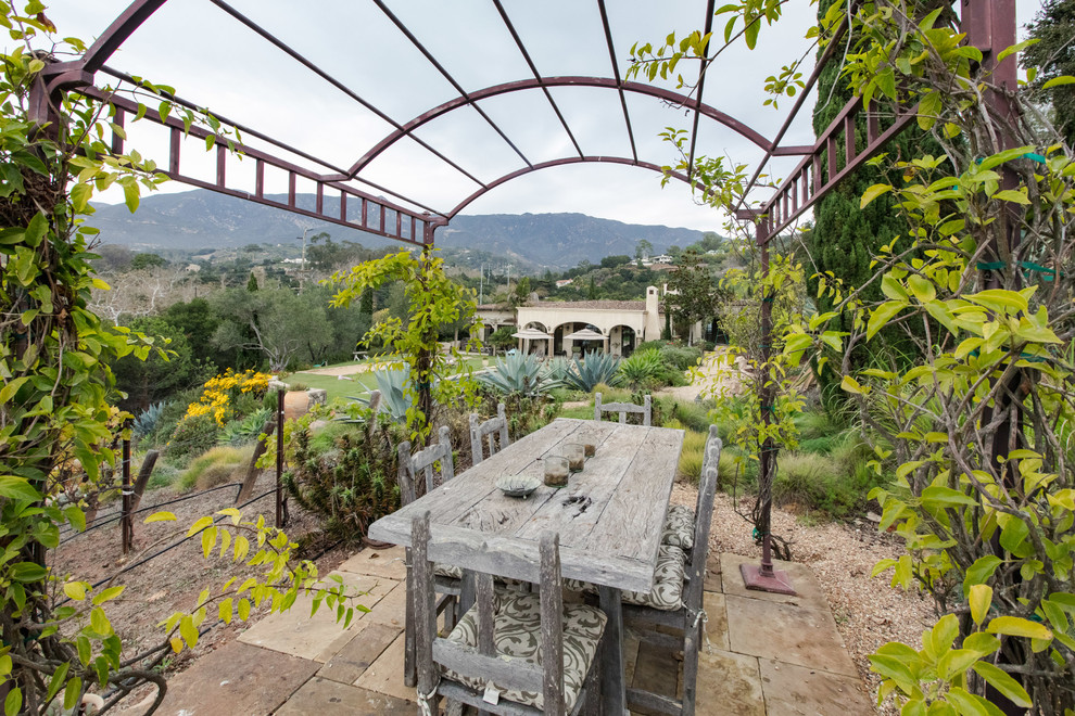 Inspiration for a mediterranean courtyard stone patio remodel in Santa Barbara with a pergola
