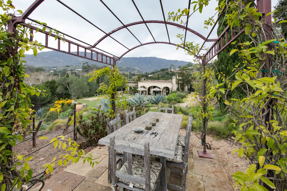サンタバーバラにある地中海スタイルのおしゃれな中庭のテラス (天然石敷き、パーゴラ) の写真