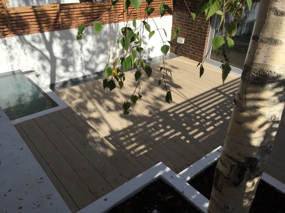 Foto de patio contemporáneo de tamaño medio sin cubierta en patio trasero con fuente y entablado