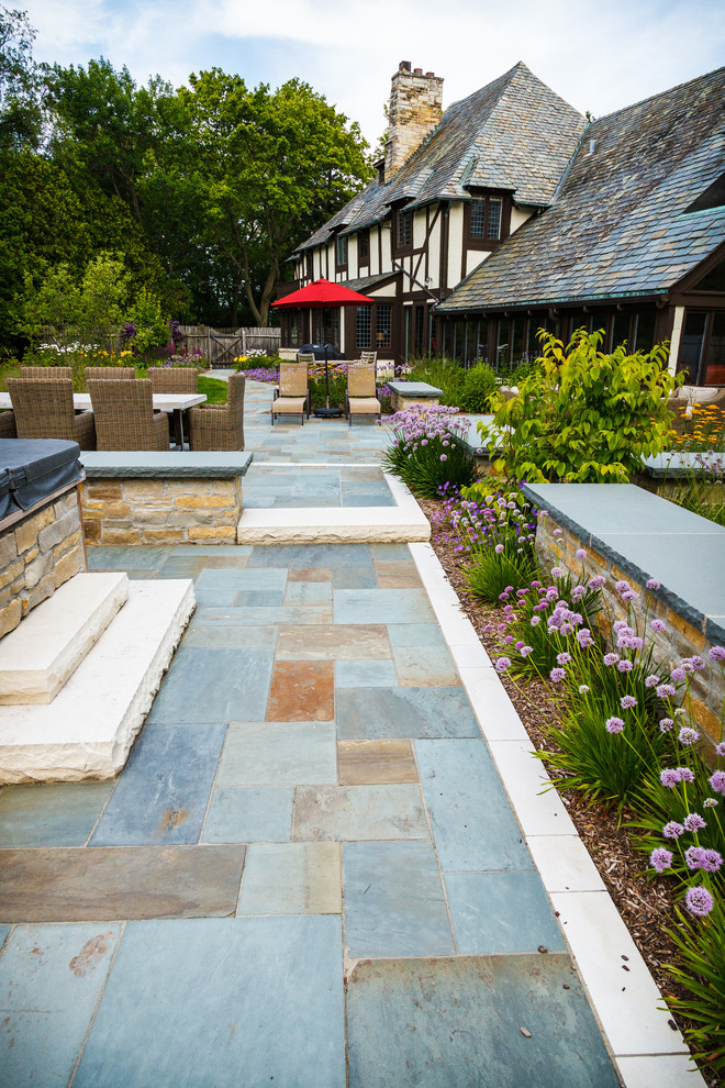 Ejemplo de patio clásico grande en patio trasero con adoquines de piedra natural y fuente