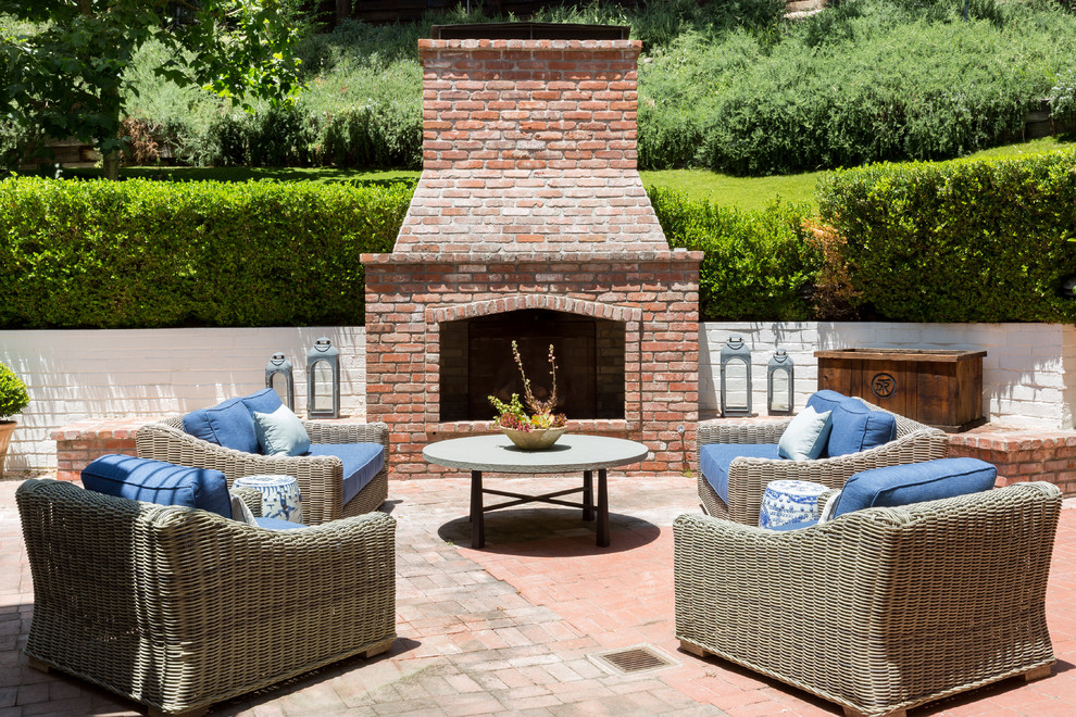 Design ideas for a large traditional back patio in Los Angeles with a fireplace, brick paving and no cover.