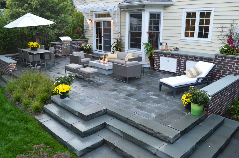 This is an example of a medium sized contemporary back patio in Chicago with an outdoor kitchen, natural stone paving and no cover.
