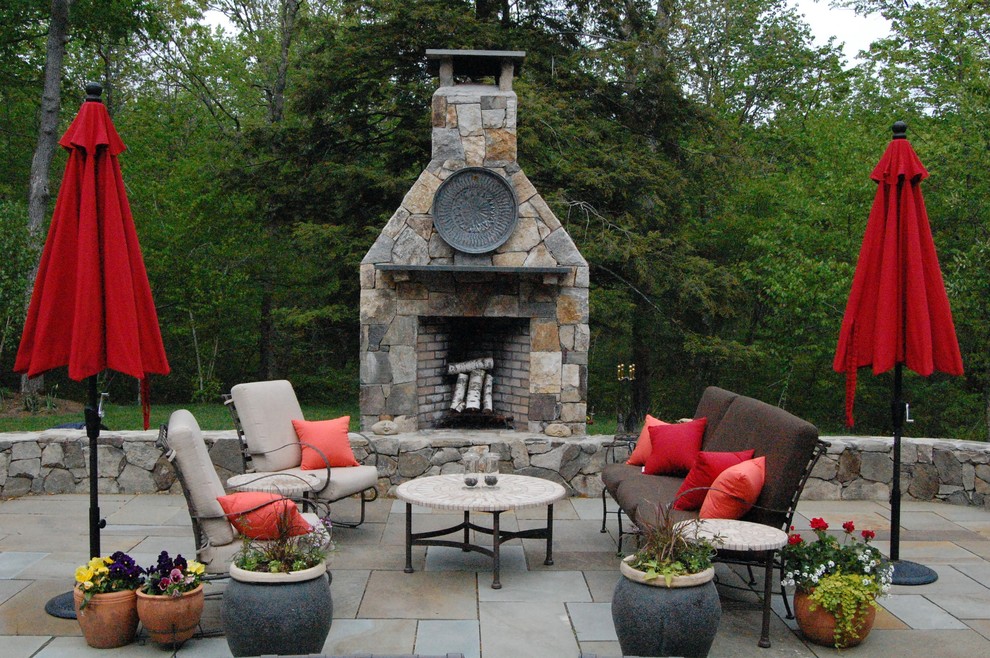 Idées déco pour une terrasse classique avec des pavés en pierre naturelle et un foyer extérieur.