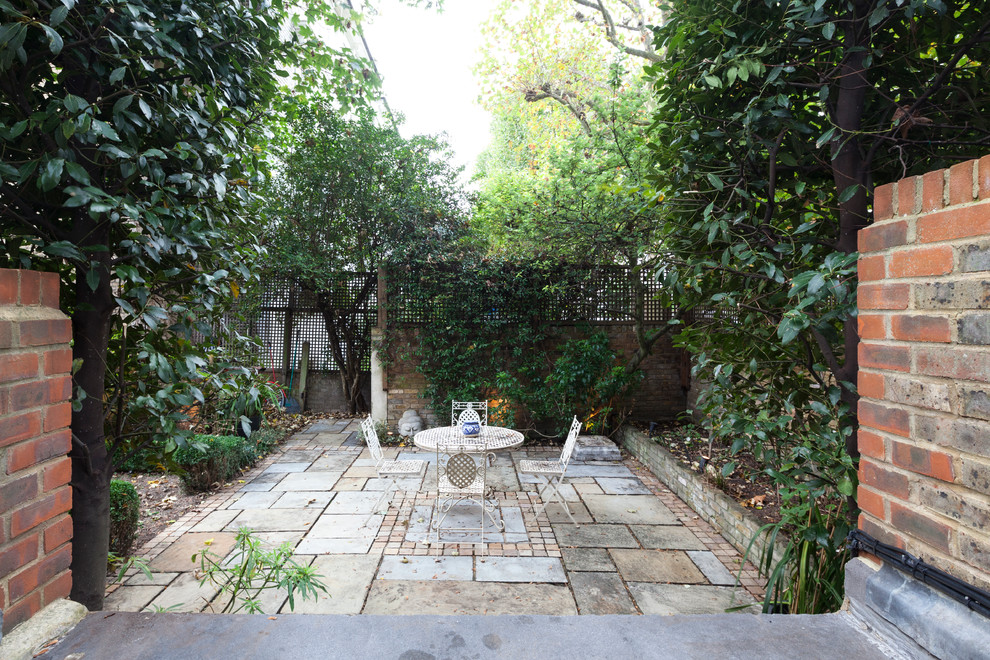 This is an example of a medium sized classic back patio in London with tiled flooring and no cover.