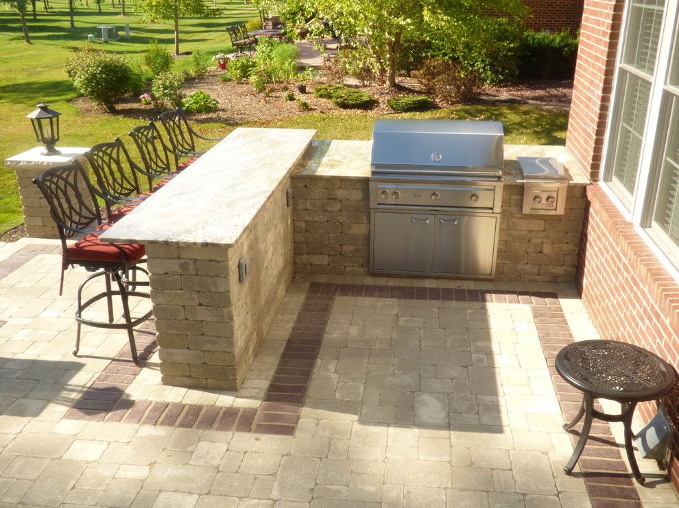 Cette photo montre une terrasse arrière chic de taille moyenne avec une cuisine d'été, des pavés en béton et aucune couverture.