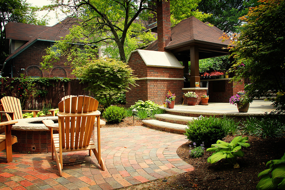 Idee per un patio o portico chic con pavimentazioni in pietra naturale, un focolare e un gazebo o capanno