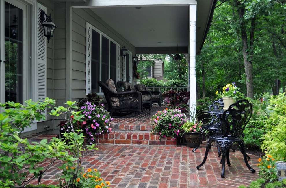 Foto di un patio o portico tradizionale di medie dimensioni e davanti casa con pavimentazioni in mattoni e un tetto a sbalzo
