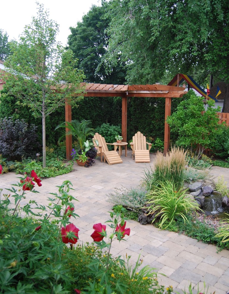 This is an example of a traditional patio in Chicago with brick paving, a pergola and a water feature.