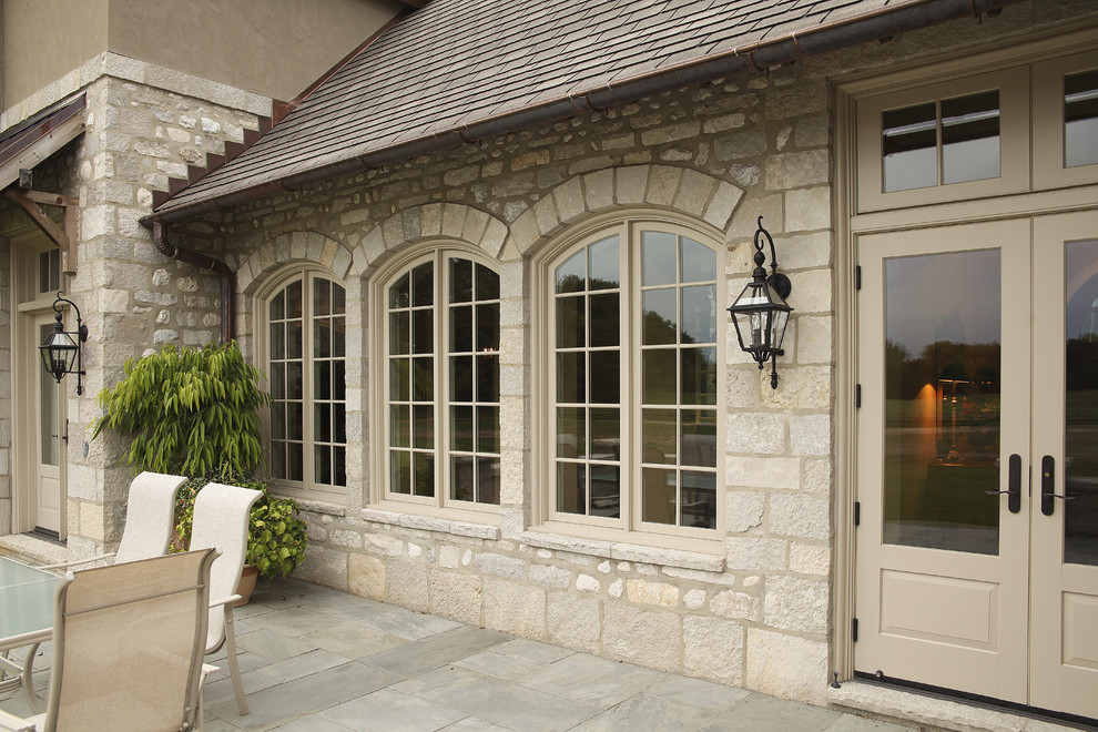 Inspiration for a huge timeless backyard stone patio remodel in Other with an awning