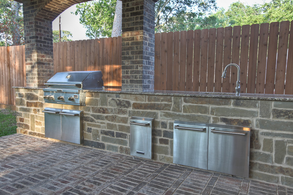 This is an example of a traditional back patio in Houston with an outdoor kitchen.